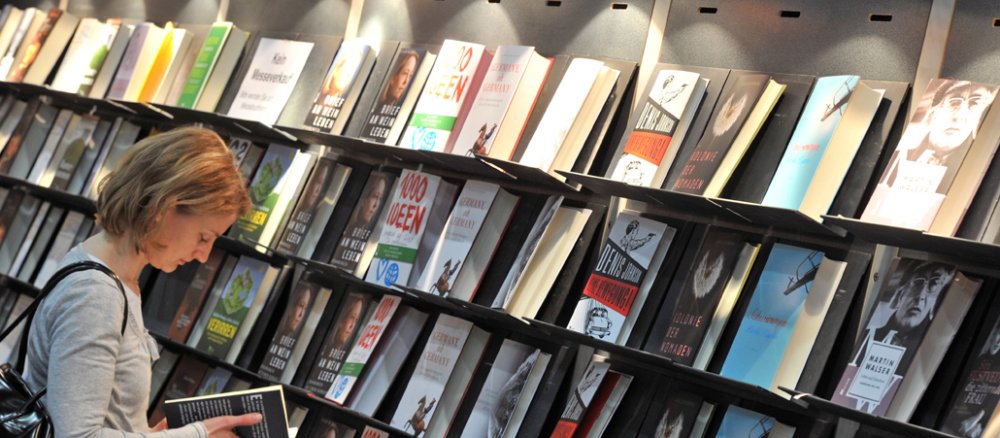 Eine junge Frau sieht sich am auf der Buchmesse in Leipzi ein Buch an.