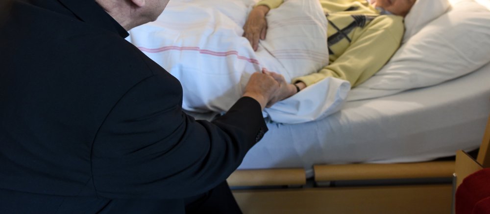 Bischof Felix Genn besucht eine Patientin in einem Hospiz in Münster.