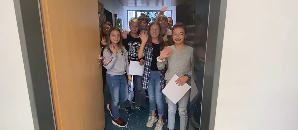 Blick durch einen Türbogen auf winkende Schülerinnen und Schüler.