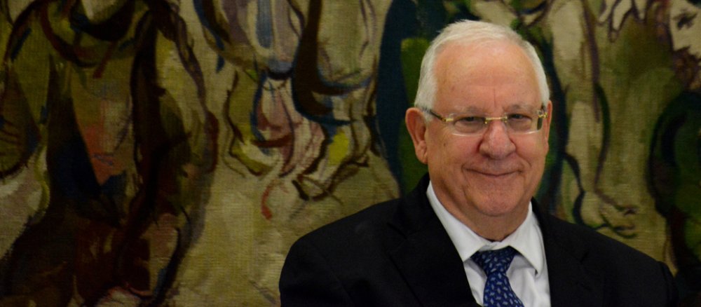 Ein älterer Mann steht vor einem Wandteppich in der Knesset.