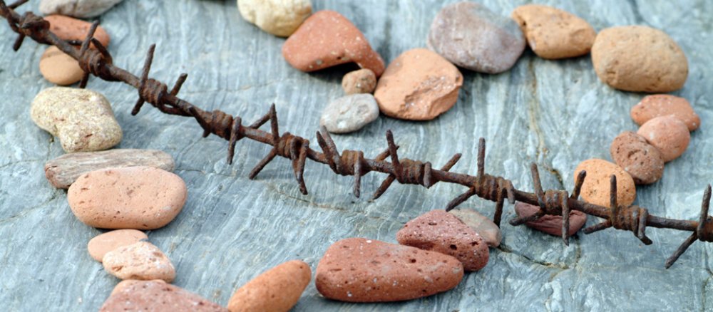 Stillleben mit Herz zusammengestellt aus Steinen und einem Stück verrosteten Stacheldraht