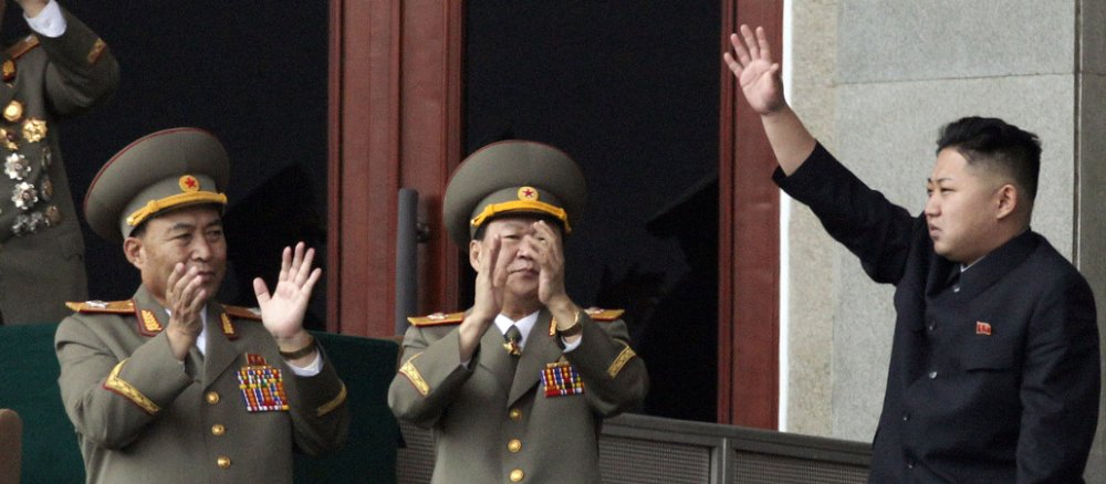 Nordkoreas Diktator Kim Jong Un winkt, hohe Militärs applaudieren.