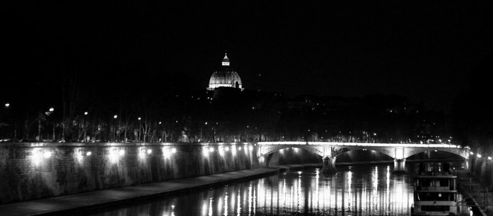 Blick auf den Petersdom über den Tiber bei Nacht.