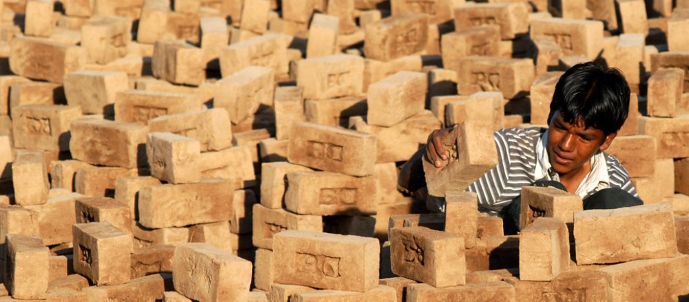Eine Junge arbeitet in Indien mit Pflastersteinen.