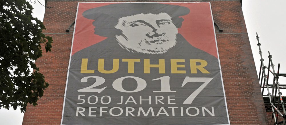Am Turm einer Kirche hängt ein großes Luther-Banner.