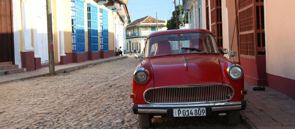 Ein roter Oldtimer in einer Straße mit bunten Häusern