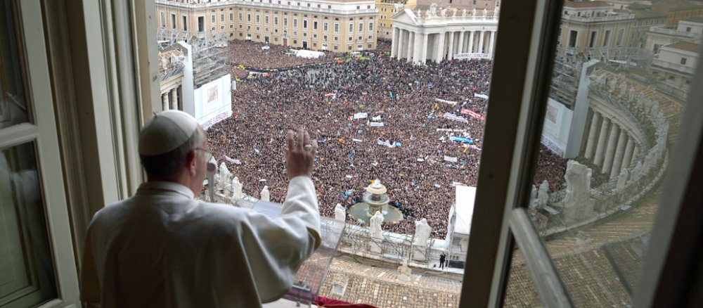 Papst Franziskus winkt vom Balkon den Menschen auf dem Petersplatz zu.
