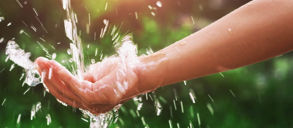 Auf eine Hand fließt Wasser.