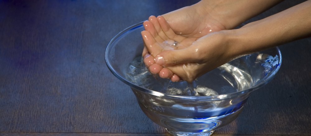 Eine Frau wäscht ihre Hände in einer Wasserschale.