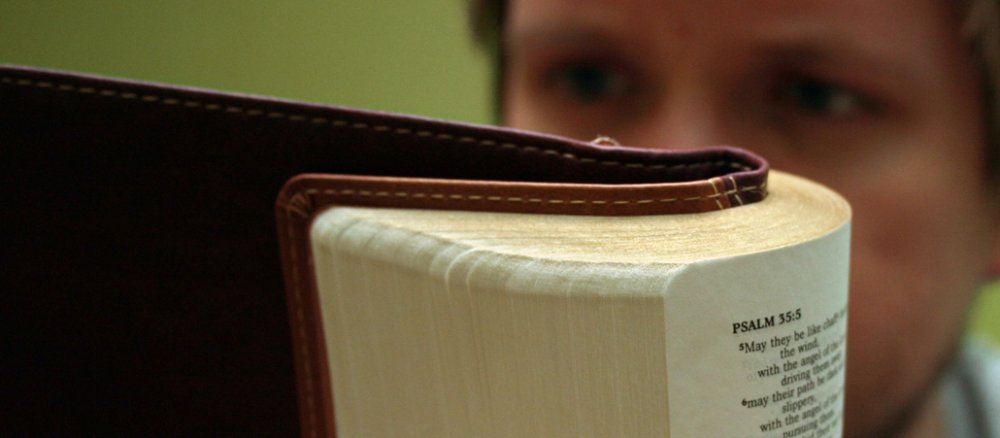 EIn junger Mann liest Psalmen in der Bibel.