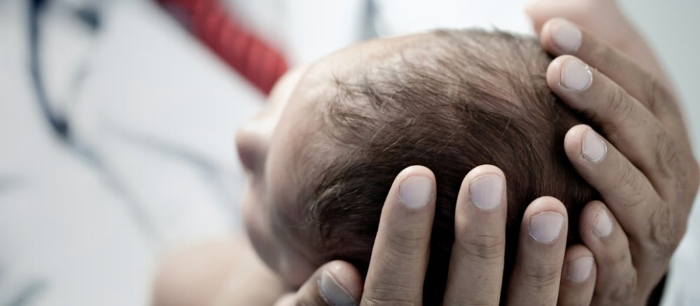 Arzt hält neugeborenes Baby in den Händen
