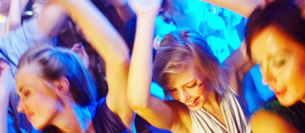 Junge Frauen tanzen am Abend während einer Party.
