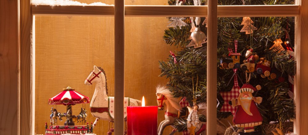 Blick durchs geschmückte Fenster auf einen Weihnachtsbaum