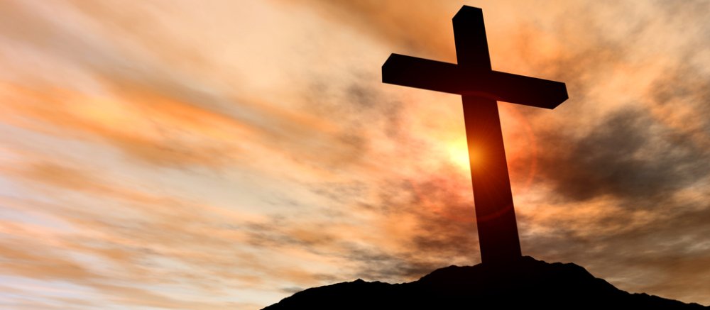 Ein Kreuz auf einem Berg im Sonnenuntergang.