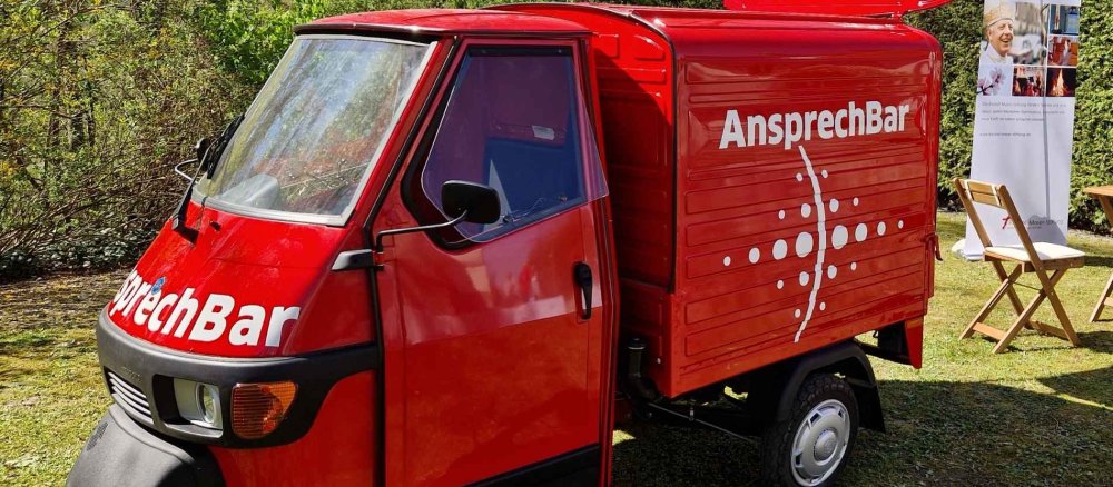 Auf dem Bild sieht man einen roten Kleinbus mit der Aufschrift "AnsprechBar"