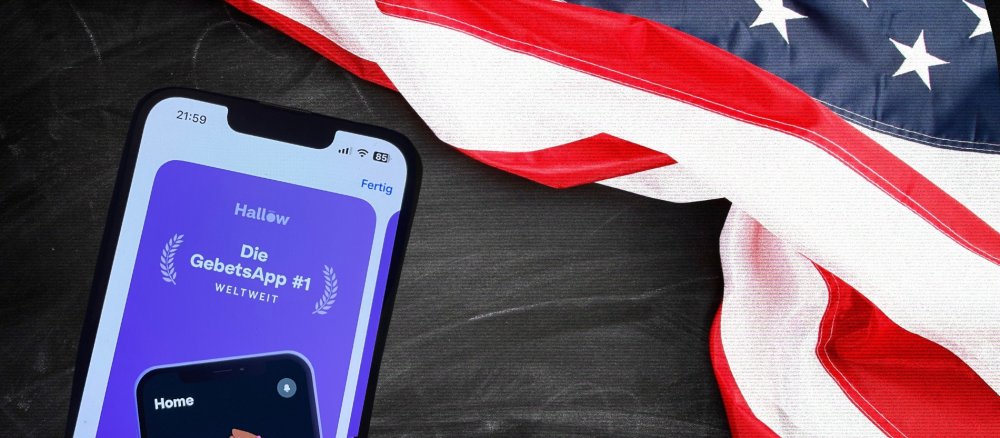 Die Gebetsapp "Hallow" neben der USA Flagge