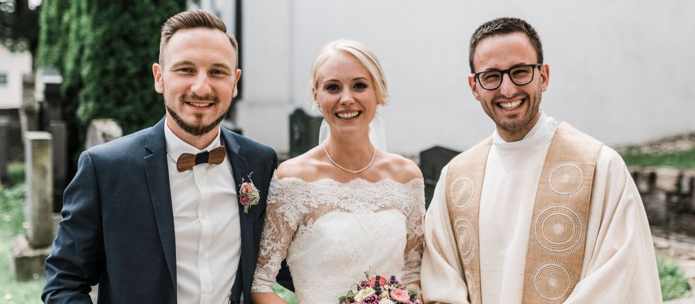 Pater Felix Biebl mit einem Hochzeitspaar vor der Abteikirche in Windberg in Bayern.