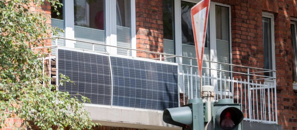 zwei Solarpanelen hängen an einem Balkon eines Wohnhauses.