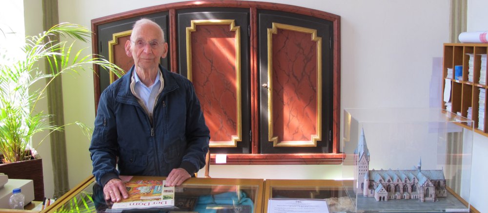 Herr Peckelsen steht hinter dem Tresen der Informationsstelle des Paderborner Domes.