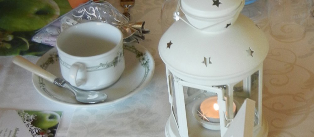 Ein dekorierter Tisch mit Windlicht, kleine Äpfeln, und verzierter Tischdecke.