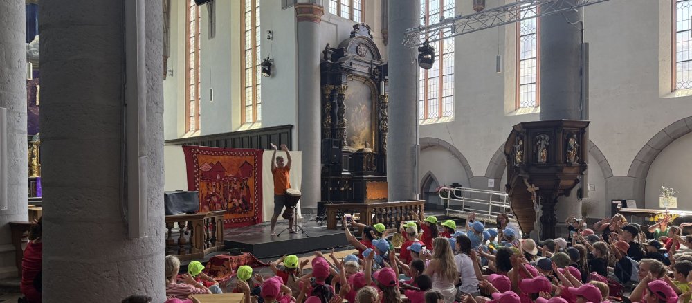 Kinder in bunten Mützen klatschen und tanzen bei einer Trommelvorführung beim Kinderpilgertag in Aachen