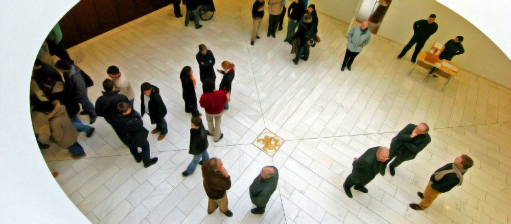 Menschen stehen im Atrium des Hörsaalgebäudes der Hochschule Sankt Georgen in Frankfurt