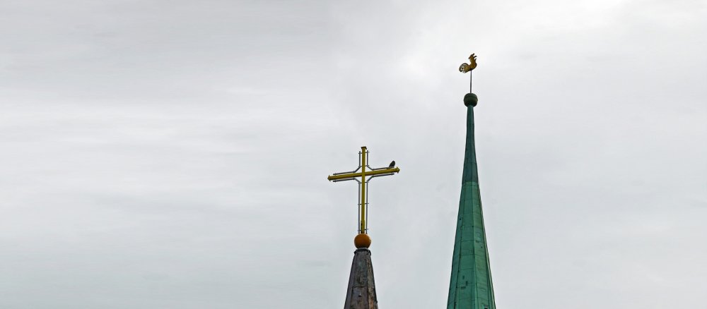 Zwei Kirchtürme in Riga, einer mit Hahn, einer mit Kreuz