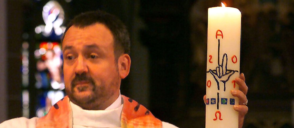 Ein Priester mit einer Osterkerze.