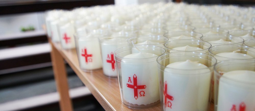 Viele kleine weiße Osterkerzen stehen auf einem Tisch in einer Kirche
