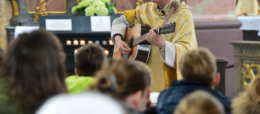 Ein Priester spielt Gitarre bei einem Familiengottesdienst am 6. April 2015 in Fulda.