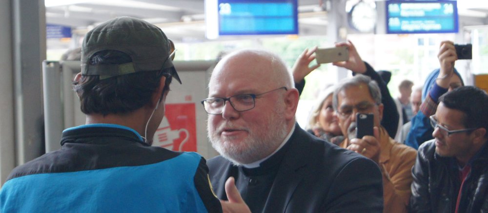 Kardinal Reinhard Marx spricht am Münchener Hauptbahnhof mit einem Flüchtling.