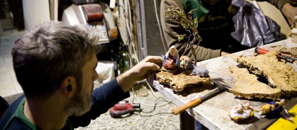 Ein Mann arbeitet in einer Werkstatt an Figuren für eine Krippe