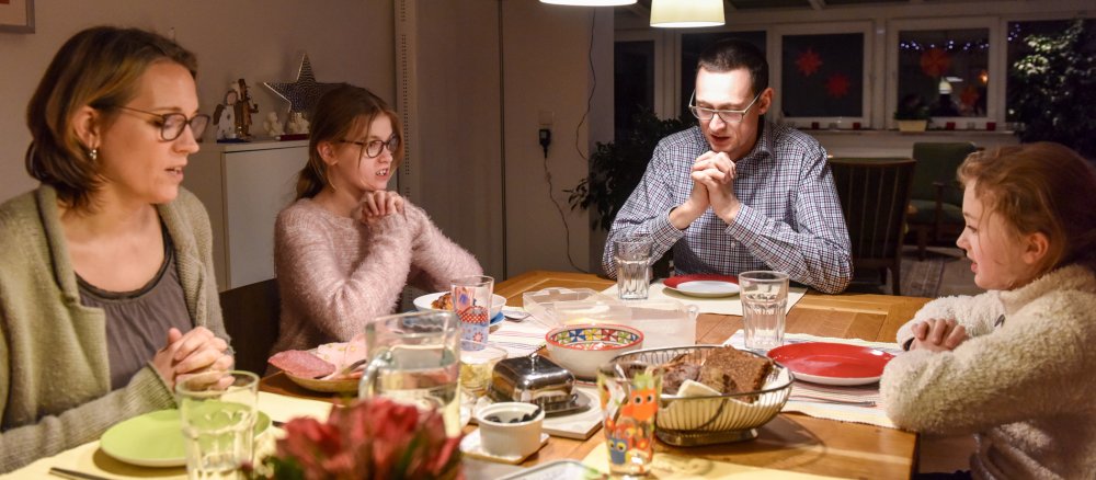 Eine Familie beim Abendessen betet