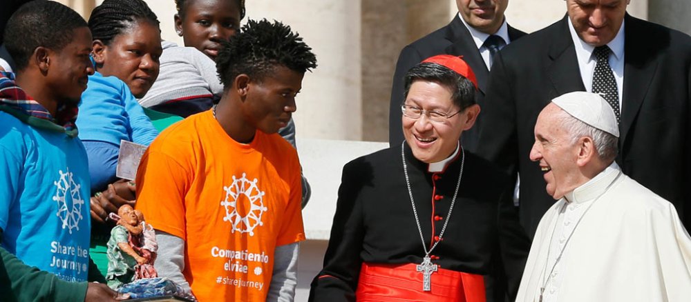 Papst Franziskus mit Kardinal Luis Antonio Tagle und Migranten
