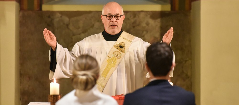 Ein Diakon spendet einem Brautpaar bei der Trauung in der Kirche Sankt Maria und Clemens in Bonn den Segen.