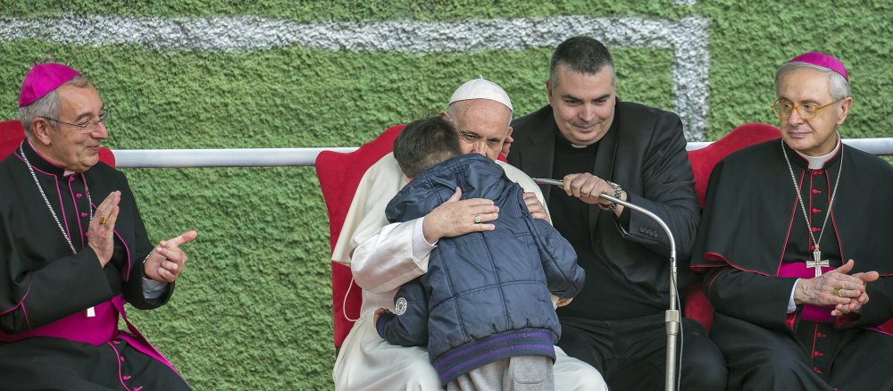 Papst Franziskus umarmt einen Jungen