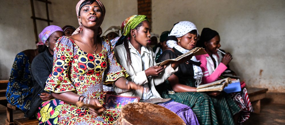 Afrikanische Frauen singen und schlagen eine Trommel