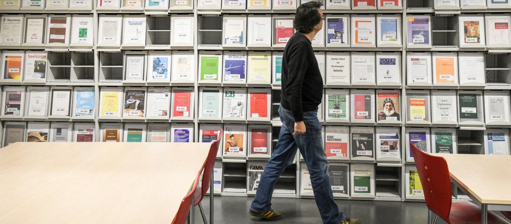 Ein Mann vor einem Regal mit theologischen Fachzeitschriften