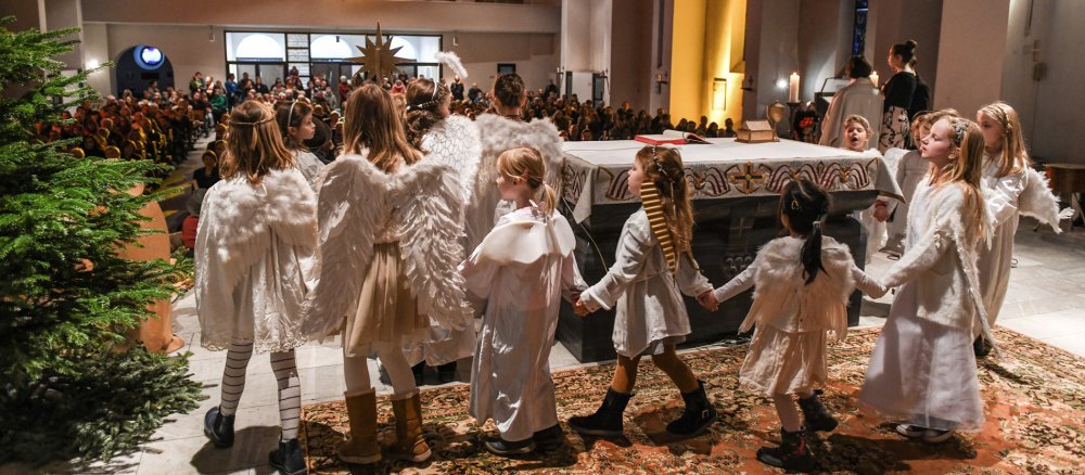 Kinder ziehen als Engel verkleidet um den Altar
