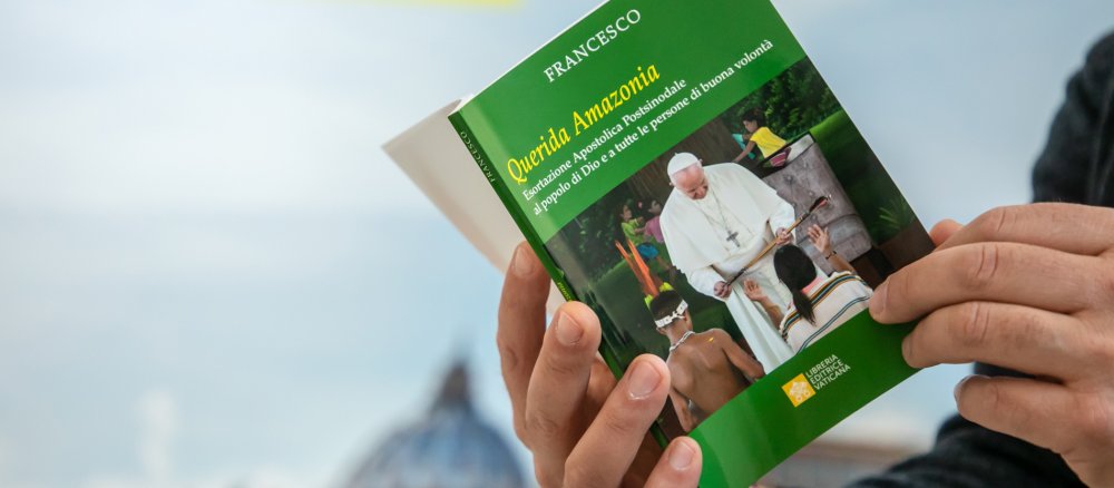 Ein Mensch blättert im Papst-Schreiben "Querida Amazonia"