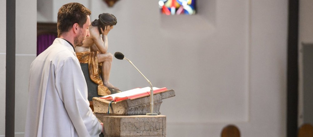 Lektor am Ambo bei einem Gottesdienst an Karfreitag in einer Kirche in Bonn.