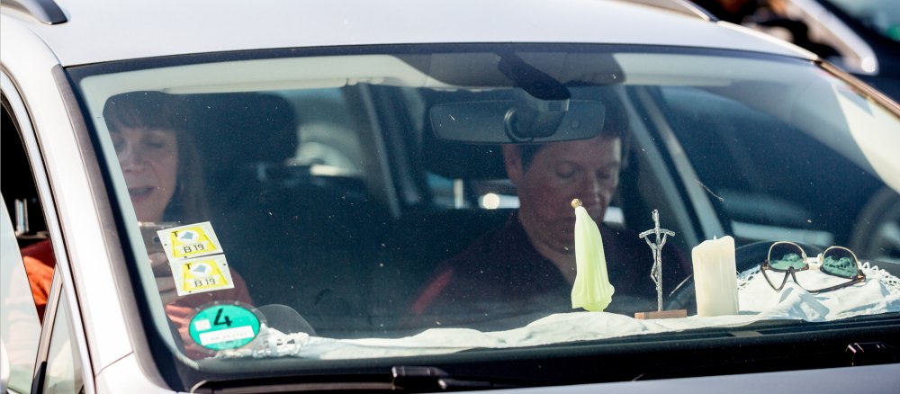 Eine kleine Madonna, ein Kruzifix und eine Kerze stehen auf dem Armaturenbrett eines Autos.