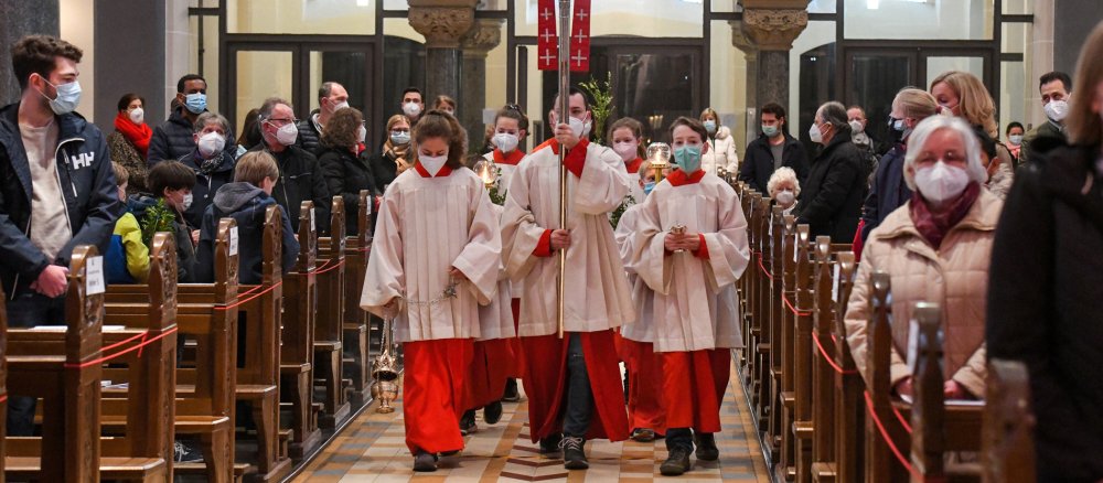 Messdiener ziehen in einer Prozession in die Kirche ein