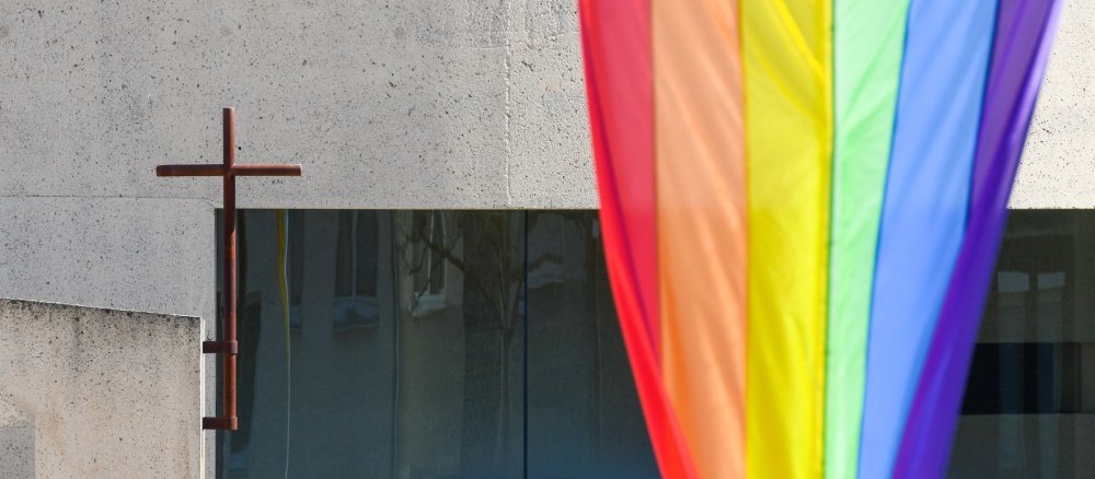 Eine große Regenbogenfahne und ein Kreuz