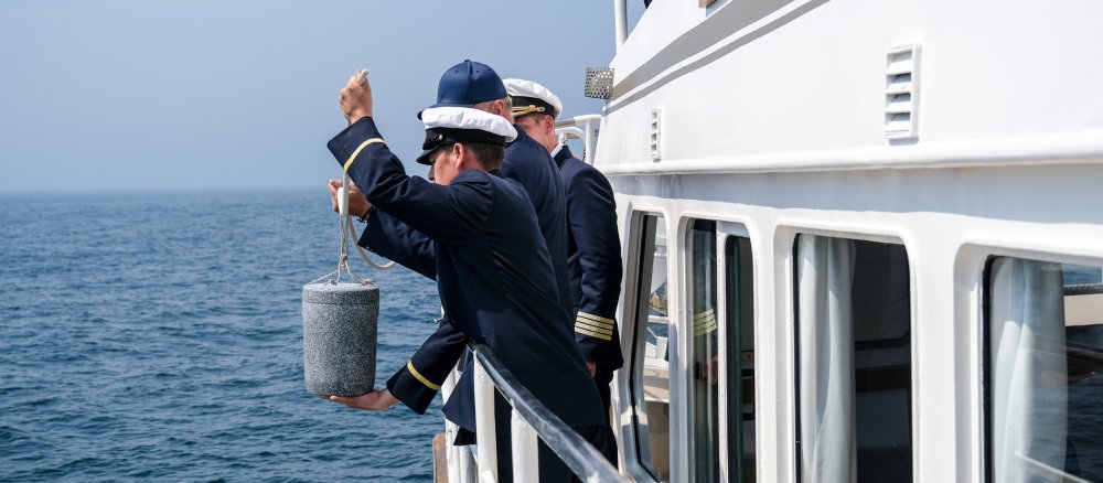 Eine Urne wird bei einer Seebestattung in die Ostsee abgesenkt