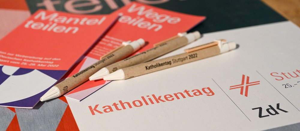 Flyer und Kugelschreiber liegen auf einem Logo des 102. Deutschen Katholikentags 2022 am 29. September 2021 auf einem Tisch in Stuttgart.