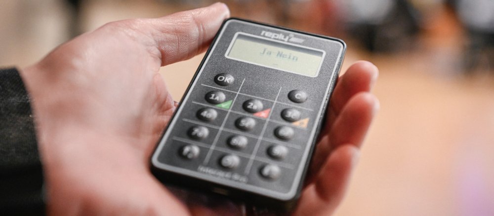 Eine Hand hält ein digitales Abstimmungsgerät