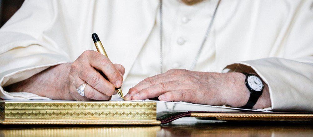 Papst Franziskus schreibt in eine Gästebuch