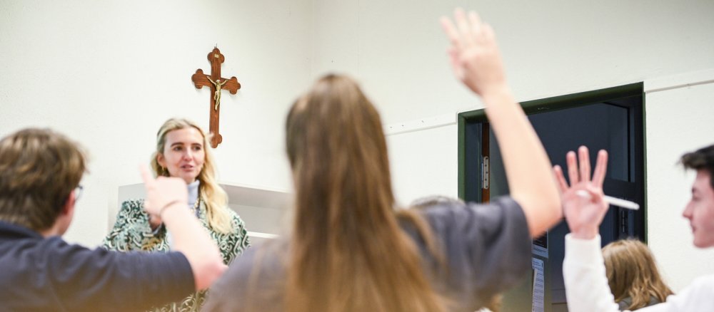 Schüler zeigen im Religionsunterricht auf