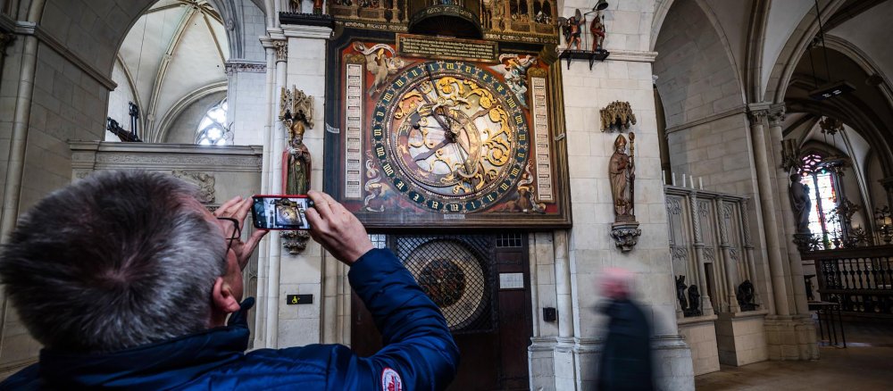 Ein Besucher macht ein Foto von der Astronomischen Uhr im Chorumgang des Sankt-Paulus-Doms in Münster.